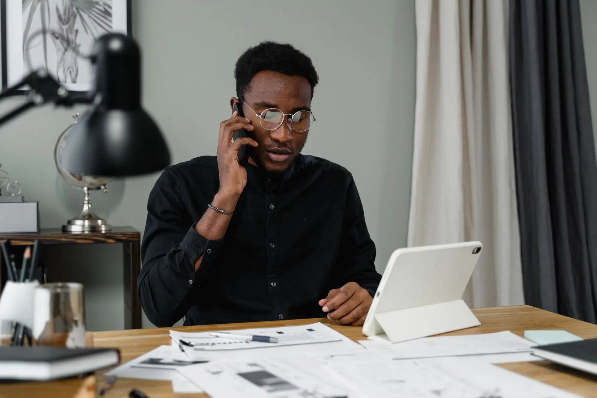 Business owner on the phone at his desk, working through bank statements and tax paperwork after a garnishee notice
