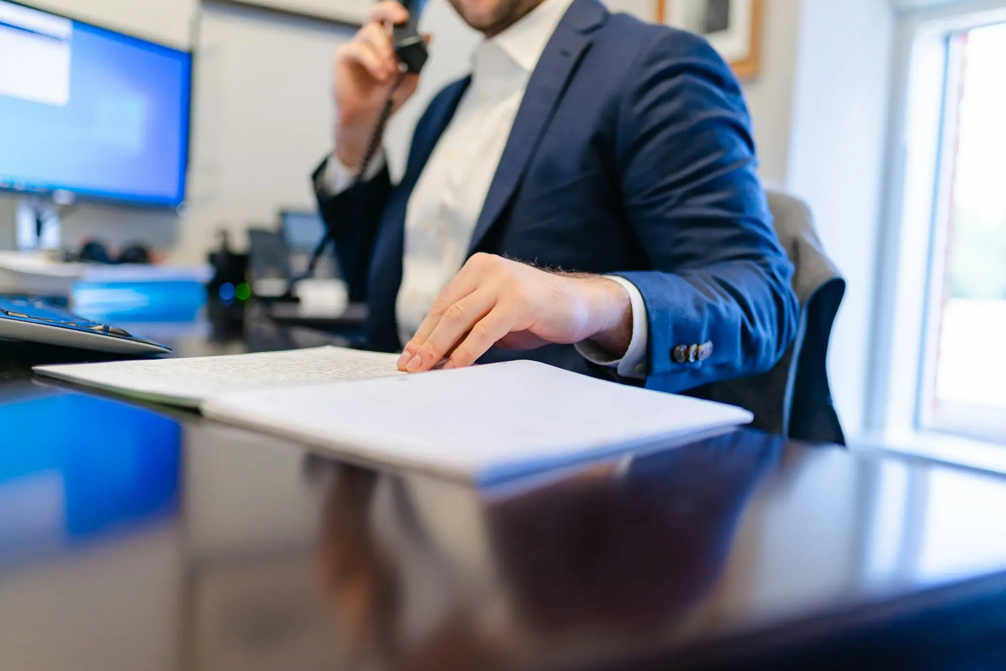 Company director on the phone at their desk, hand resting on handwritten notes about a tax payment plan